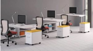 Images shows multiple workstations in an office focusing on the adjustable height desks.